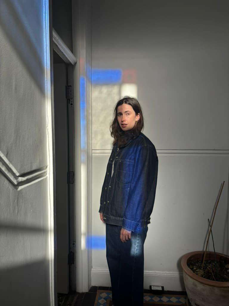 Ana Dunne Sequi glancing over her shoulder in a white hallway, blue light falling across the wall